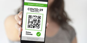 Unrecognizable young woman showing on her smartphone screen a certificate of immunity against Covid19. Concept of travel and health protocols during the corona virus pandemic.