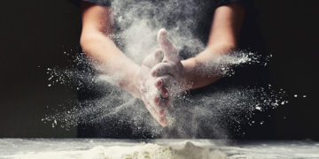 Clap hands of baker with flour in restaurant kitchen